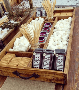 Outdoor movie night for families snack station with marshmallows, graham crackers, Hershey bars, and skewers