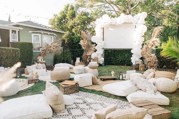 Cozy backyard setup with cushions and balloons for outdoor movie night for families in a green garden