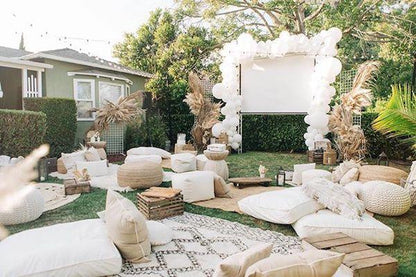 Cozy backyard setup with cushions and balloons for outdoor movie night for families in a green garden