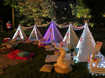 Cozy outdoor movie night for families setup with illuminated tents, cushions, and blankets in a garden